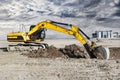 A powerful caterpillar excavator digs the ground against the evening sunset. Earthworks with heavy equipment at the construction Royalty Free Stock Photo