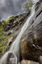 Powerful Chungulj waterfall streaming down the red cliff and dramatic sky