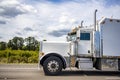 Powerful big rig classic semi truck tractor with vertical pipes and dimensional lighting side lights running on the wide highway Royalty Free Stock Photo