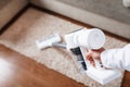 Powerful cordless vacuum cleaner with white cyclonic dust collection technology in hand, cleans the carpet in the house