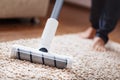 Human legs and a white turbo brush of a cordless vacuum cleaner cleans the carpet in the house Royalty Free Stock Photo