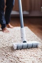 Human legs and a white turbo brush of a cordless vacuum cleaner cleans the carpet in the house Royalty Free Stock Photo