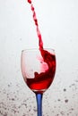 Powerful curved splash of red wine in a glass with a colored leg Royalty Free Stock Photo