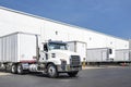 Powerful day cab big rig white semi truck tractor hooks a loaded dry van semi trailer in warehouse dock gates area Royalty Free Stock Photo