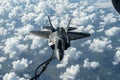 A powerful fighter jet speeds through a cloudy blue sky, creating an awe-inspiring sight, A fighter aircraft in mid-air refueling Royalty Free Stock Photo