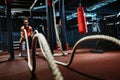 Powerful attractive muscular woman battle rope workout at the gym