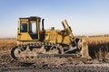 Powerful heavy crawler bulldozer works at a construction site in the evening against the background of the sunset sky. Royalty Free Stock Photo