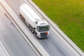 Powerful heavy white truck with a tank for flammable liquids rides on the road, aerial front view Royalty Free Stock Photo