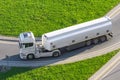 Powerful heavy white truck with a tank for flammable liquids rides turn on the road, close up view Royalty Free Stock Photo