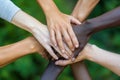 A powerful image of unity with diverse hands joined together over a green natural background. Team work together concept