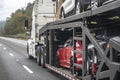 Powerful industrial big rig car hauler semi truck transporting cars on the modular semi trailer running on the wide road Royalty Free Stock Photo