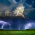 Powerful lightnings in dark stormy sky above green grass hills