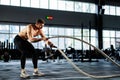 powerful man training battle ropes at cardio workout in dark gym. Professional athlete exercise fitness sport club equipment. Royalty Free Stock Photo