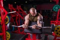 Powerful muscular man doing biceps exercise with barbell on the bench Royalty Free Stock Photo