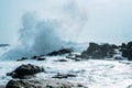 Powerful ocean wave splashes across a big rock.