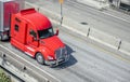 Powerful red big rig long haul semi truck transporting cargo in semi trailer running on the divided highway Royalty Free Stock Photo