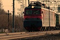 A powerful red diesel locomotive pulls a long freight train along the tracks