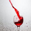 Powerful splash of red wine in a glass on a gray background