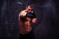 Powerful sportsman practicing a jab in black boxing gloves over