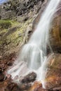 Powerful sunlit waterfall splashing on the rock creating a rainbow Royalty Free Stock Photo