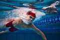 Powerful strokes pf swimmer developing speed. Young swimming male athlete in motion, in cap and goggles in swimming pool