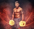 Handsome shirtless tattooed bodybuilder with stylish haircut and beard, wearing sports shorts, posing in a studio. Fire