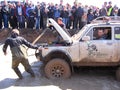 Powerful SUV overcome a rocky slope at the races the crowd of people, the audience watching the spectacle