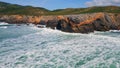 Powerful swell hitting rocky coast with splashes rolling white foam drone view. Royalty Free Stock Photo