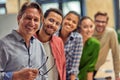 Powerful team. Group of young happy multiethnic colleagues smiling at camera while standing in the modern office Royalty Free Stock Photo