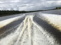 Powerful traces of a jet on the water from a moving boat along the river Royalty Free Stock Photo