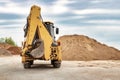 Powerful universal loader or excavator with folded bucket at construction site. Back view. Powerful modern equipment for