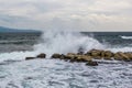 Powerful wave in sea crashing against rock sending up sprays of white foam in sky with cirrus clouds seagull above horizon line Royalty Free Stock Photo