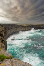 Powerful waves hist rocks at the bottom of cliff. Inishmore, Aran islands, county Galway, Ireland. Cloudy sky. Nobody. Nature