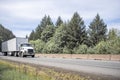 Powerful white day cab big rig semi truck transporting cargo in dry van semi trailer running on the highway road for local Royalty Free Stock Photo