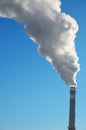 Smoke rises up from chimney against blue sky