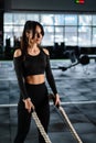 Powerful woman training battle ropes at cardio workout in dark gym. Professional athlete exercise fitness sport club equipment. Royalty Free Stock Photo