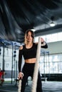 Powerful woman training battle ropes at cardio workout in dark gym. Professional athlete exercise fitness sport club equipment. Royalty Free Stock Photo