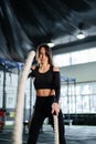 Powerful woman training battle ropes at cardio workout in dark gym. Professional athlete exercise fitness sport club equipment. Royalty Free Stock Photo