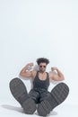 Powerful young man flexing biceps and showing boots while sitting Royalty Free Stock Photo