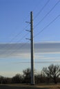 A Powerline metal pole with cables and blue sky with clouds and trees Royalty Free Stock Photo