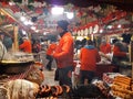 People fry grilled sausages on big hanging grill at Christmas market Royalty Free Stock Photo