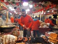 People fry grilled sausages on big hanging grill at Christmas market