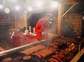 People fry grilled sausages on big hanging grill at Christmas market in Poznan