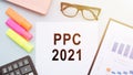 PPC Pay Per Click is an acronym written on white paper on an office desk with a calculator, markers, glasses and financial Royalty Free Stock Photo