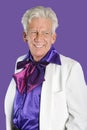 Portrait of happy senior man wearing old-fashioned suit against purple background