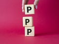 PPP private public partnership symbol. Wooden cubes with words PPP. Businessman hand. Beautiful red background. Business and PPP