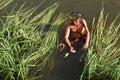 Fisherman pulls a fish out of harpoon in marsh