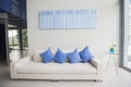 Prachuap Khiri Khan, Thailand-November 10, 2020: long white cozy sofa with blue pillows and blue frame hanging on a wall