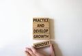 Practice and Develop growth mindset symbol. Wooden blocks with words Practice and Develop growth mindset. Businessman hand.