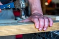Finishing nail being driven in with a hammer while a hand supports the board Royalty Free Stock Photo